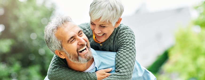 Life Assure Seniors Couple Piggyback Walk In Park Hero